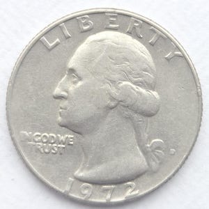 Może przedstawiać: Srebrna moneta ćwierćdolarowa z 1972 roku, przedstawiająca profil George'a Washingtona. Słowo "LIBERTY" jest wygięte nad portretem, z napisami "IN GOD WE TRUST" i datą "1972" również widocznymi.