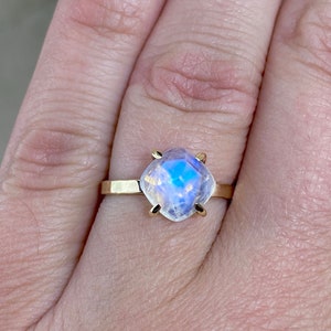 High Quality AAA quality blue flash rainbow Moonstone gemstone solitaire ring shown on models hand.