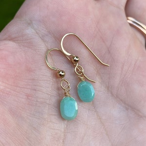May include: A pair of gold earrings with small, teardrop-shaped green gemstones.