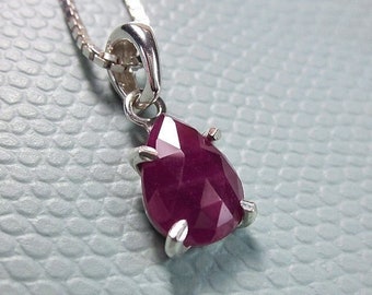May include: A silver chain necklace with a pear-shaped ruby pendant.