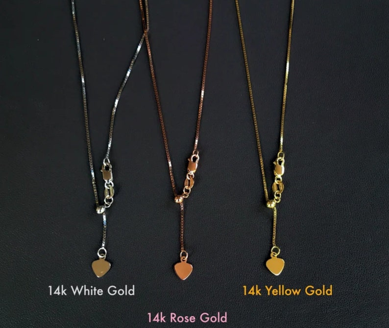 K&ouml;nnte beinhalten: Drei Halsketten aus Wei&szlig;-, Ros&eacute;- und Gelbgold mit Herzanh&auml;ngern. Die Ketten sind vor dunklem Hintergrund abgebildet, mit den Bezeichnungen: 14k White Gold, 14k Rose Gold und 14k Yellow Gold. Die Ketten haben feine Glieder.