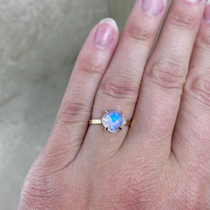 High Quality AAA quality blue flash rainbow Moonstone gemstone solitaire ring shown on models hand.
