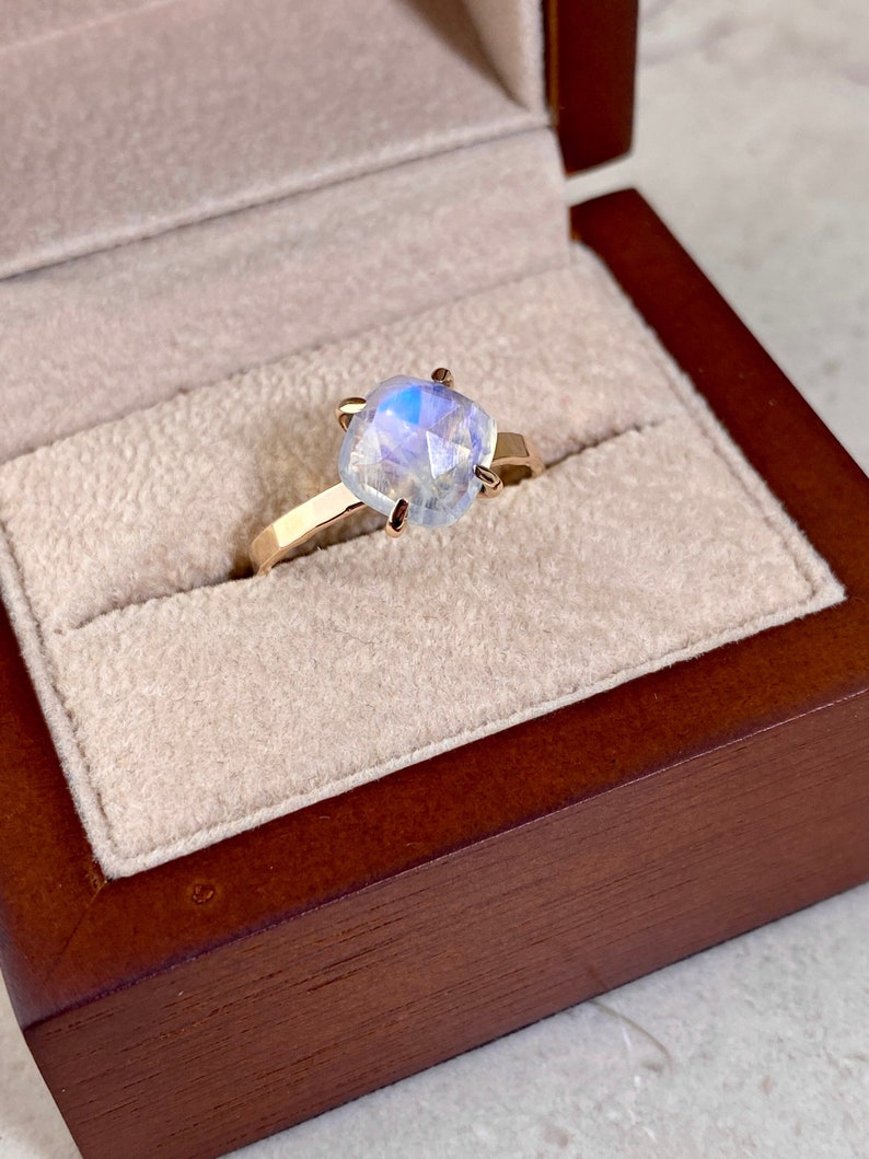High Quality blue flashing cushion shape moonstone solitaire ring shown in gift box ready to gift. Perfect dainty delicate jewelry gift for her. Great earring present for birthday, wedding, anniversary, baby shower and June Birthdays.