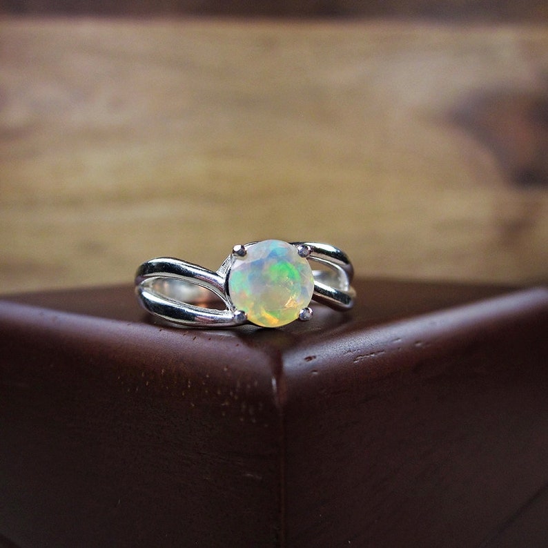 Puede incluir: Un anillo de plata con una piedra de &oacute;palo blanco engastada en una banda retorcida.