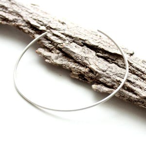 Puede incluir: Un collar fino de plata, descansando sobre un trozo de madera a la deriva desgastada.