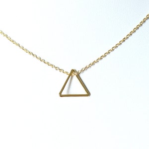 Può includere: Una collana con catena dorata e un ciondolo a forma di triangolo geometrico semplice.
