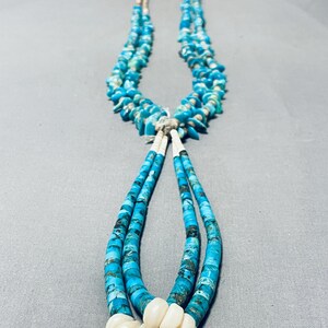 May include: A turquoise and white beaded necklace with a long, dangling strand of turquoise beads. The necklace is made of multiple strands of beads, with a cluster of white beads at the bottom.