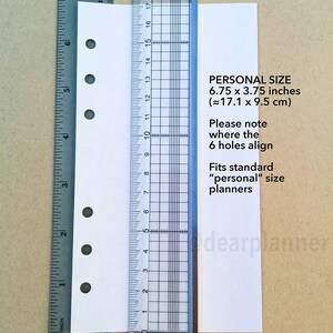 May include: A white sheet of paper with six holes punched along the left edge. The paper is measured with a ruler, showing it is 6.75 inches by 3.75 inches. The text on the paper reads "PERSONAL SIZE 6.75 x 3.75 inches (&asymp;17.1 x 9.5 cm) Please note where the 6 holes align Fits standard "personal" size planners".