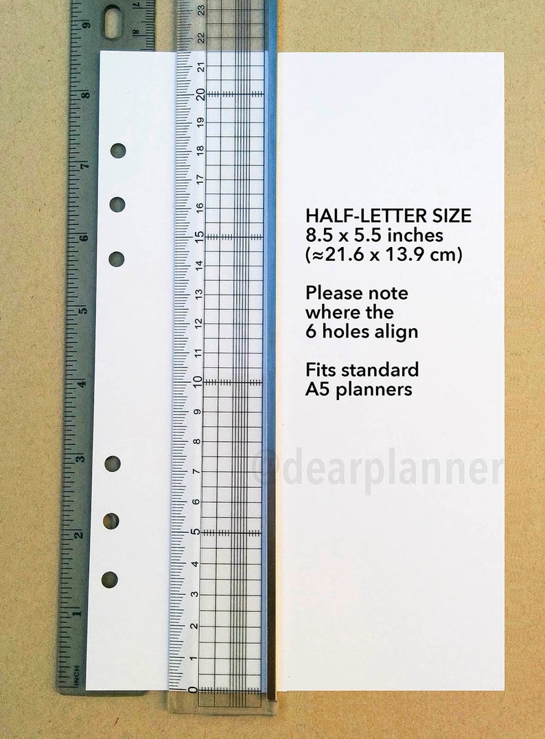 May include: A white sheet of paper with six holes punched along the left edge. The paper is measured with a ruler showing it is 8.5 inches by 5.5 inches. The text "HALF-LETTER SIZE 8.5 x 5.5 inches (&asymp;21.6 x 13.9 cm) Please note where the 6 holes align Fits standard A5 planners dearplanner" is printed on the paper.