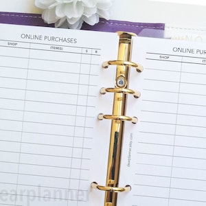 May include: A white planner page with a gold binder ring. The page is divided into columns labeled "Shop", "Item(s)", "S", and "R". The text "ONLINE PURCHASES" is at the top of the page.