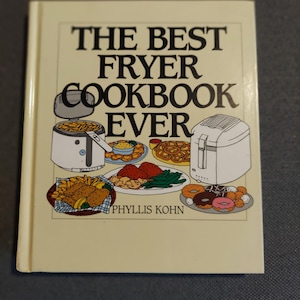 May include: A hardcover cookbook titled The Best Fryer Cookbook Ever by Phyllis Kohn. The off-white cover features illustrations of two white deep fryers surrounded by plates of fried foods including french fries, onion rings, and donuts.