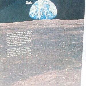 K&ouml;nnte beinhalten: Eine Illustration der Erde, einer blau-wei&szlig;en Kugel, die &uuml;ber einer grauen, strukturierten Oberfl&auml;che aufsteigt. Das Wort "Gaia" steht oben. Der Text darunter beschreibt die Gaia-Hypothese und die Arbeit von James Lovelock.