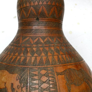 Calabaza keniana vintage de 23 cm de alto, con pátina envejecida y diseños de animales intrincadamente tallados: elefantes, cebras y rinocerontes.