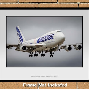 May include: A white Boeing 747-412(BCF) cargo plane with blue and white markings, labeled "National Airlines" on the side, is landing. The plane is in mid-air, with its landing gear extended.