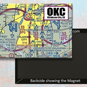 Puede incluir: Un imán colorido que presenta un mapa detallado del área de Oklahoma City con el texto "OKC Oklahoma City, OK" en un rectángulo negro. El mapa incluye códigos de aeropuerto, información sobre pistas y otros detalles de aviación.