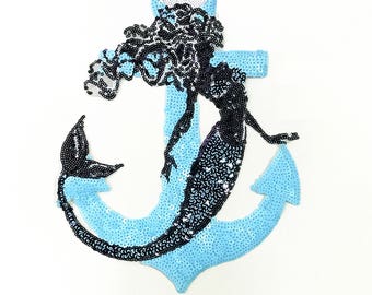 May include: A blue and black sequined iron-on patch featuring a mermaid with long hair wrapped around an anchor.