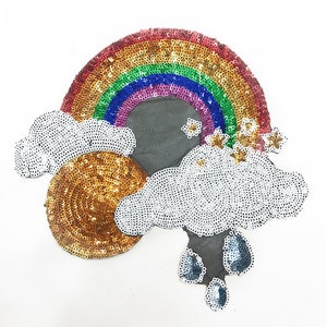 May include: A rainbow, clouds, sun, and raindrops made of sequins. The rainbow is multi-coloured, the clouds are white, the sun is gold, and the raindrops are blue.