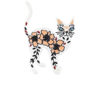 May include: A white cat with orange and black markings is decorated with peach and black flowers. The cat is outlined with black and red beads.