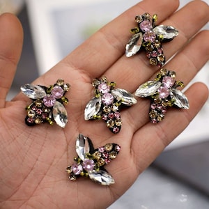 Könnte beinhalten: Fünf glitzernde bienenförmige Verzierungen mit klaren, rosa und goldenen Strasssteinen. Die Verzierungen sind perfekt, um Kleidung, Taschen oder anderen Bastelarbeiten einen Hauch von Glanz zu verleihen.