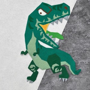 May include: Green felt dinosaur applique with a yellow mouth and white eyes. The dinosaur is facing right and has a fierce expression.