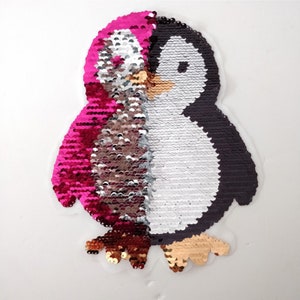 Op de afbeelding: Een roze en zwarte sequin pinguïn patch. De pinguïn kijkt naar rechts en heeft een witte buik en zwarte ogen. De patch is gemaakt van omkeerbare sequins, dus je kunt ze omdraaien om de kleur te veranderen.