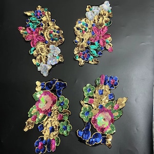 May include: Four floral embellishments featuring sequins in gold, pink, blue and green. The embellishments are made of sequins and beads and are ideal for adding a touch of sparkle to any project.