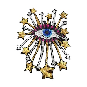 May include: A large, colourful eye with a blue iris and pink eyelids surrounded by gold and silver sequins in the shape of stars.