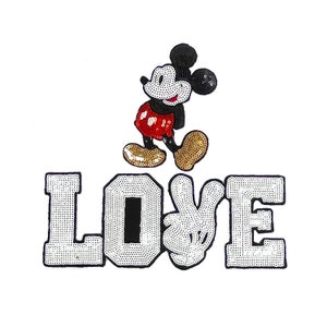 Puede incluir: Un parche blanco para planchar con la palabra "LOVE" en lentejuelas blancas con contorno negro. Mickey Mouse está de pie sobre la palabra "LOVE" con los brazos extendidos. Mickey Mouse también está hecho de lentejuelas.