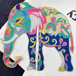 May include: A colourful embroidered elephant patch featuring intricate floral designs in shades of pink, blue, green, yellow, and gold. The patch is made of fabric and is ideal for adding a touch of whimsy to clothing, bags, or other crafts.