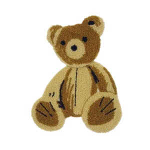 Op de afbeelding: Een bruine pluche teddybeer met zwarte ogen en een gestikte glimlach. De beer zit met gekruiste benen en zijn armen langs zijn zijde.