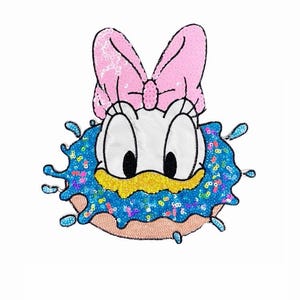 Può includere: Una toppa con paillettes raffigurante un personaggio dei cartoni animati con un fiocco rosa, grandi occhi e un becco giallo. Il personaggio è circondato da un motivo a spruzzo blu con paillettes e si trova sopra una ciambella color beige.