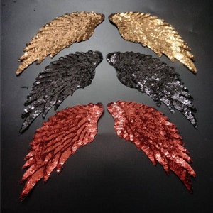 Puede incluir: Cuatro pares de alas de ángel de lentejuelas en dorado, negro, rojo y burdeos. Las alas están hechas de lentejuelas y son perfectas para añadir un toque de brillo a cualquier proyecto.