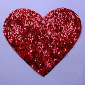 May include: A red heart-shaped sequin patch. The sequins are small and densely packed, creating a shimmering effect.