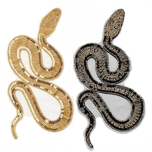 May include: Two beaded snake patches. One is gold with black accents, the other is black and gold. The snakes are in a coiled position, with detailed beadwork and sequin embellishments. The patches are on a white background.