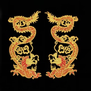 Może przedstawiać: Dwie haftowane aplikacje smoków w kolorze złotym i czerwonym z misternymi detalami. Smoki są zwrócone w przeciwne strony i mają tradycyjny chiński wzór.