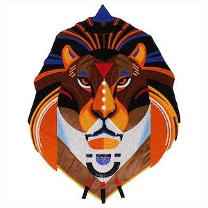 May include: Geometric embroidered lion head patch with a brown, orange, blue and white colour scheme. The lion's mane is stylised with geometric shapes and the lion's face is detailed with white dots and a triangle nose.
