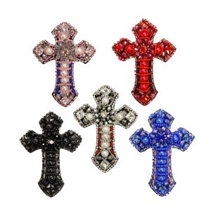 May include: Five beaded cross embellishments in different colors. The crosses are made of beads in shades of pink, red, black, silver, and blue.