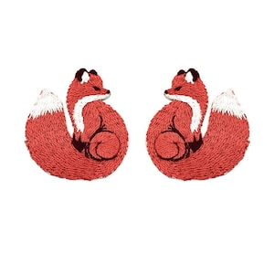 Op de afbeelding: Twee rode geborduurde vossenpatches met witte staarten. De vossen zijn opgerold met hun staarten om hun lichaam gewikkeld.