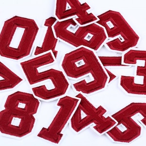 Op de afbeelding: Een set van tien rode vilt strijk-op patches met witte randen, elk met een ander nummer van 0 tot 9.