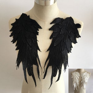 May include: Two black lace angel wings with a feathered design. The wings are attached to a white mannequin.