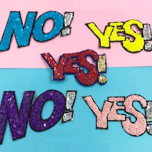 Könnte beinhalten: Fünf Bügelbilder mit den Worten "YES!" und "NO!" in verschiedenen Farben. Die Patches sind aus Pailletten gefertigt und haben eine Comic-Schriftart.