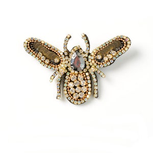 May include: A gold and black bee brooch with iridescent rhinestones and a large, faceted, dark grey gem in the centre.