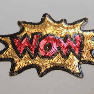 Peut inclure: Patch thermocollante en sequins dorés et rouges avec le mot "WOW" dans une bulle de dialogue de style bande dessinée.
