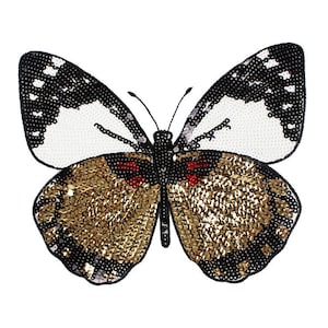 May include: A decorative butterfly applique with a detailed design. The wings feature white and black beaded sections, with a gold sequined body and red accents. The butterfly is set against a white background.