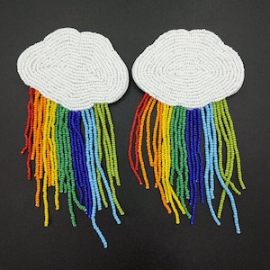 Può includere: Un paio di orecchini a forma di nuvola in perle bianche con frange di perle arcobaleno.