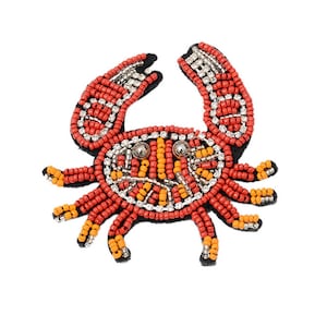 May include: A red, orange, and silver beaded crab applique. The crab is made of small beads and has a detailed design.