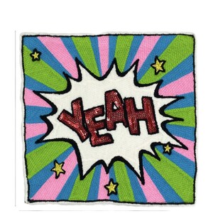 Puede incluir: Un parche bordado blanco y rojo con la palabra "YEAH" en lentejuelas rojas sobre un fondo blanco. El parche est&aacute; rodeado por un dise&ntilde;o a rayas verde, azul y rosa con estrellas doradas.