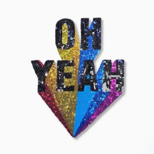 Op de afbeelding: Een pailletten pijlontwerp met de woorden "OH YEAH" in het zwart. De pijl is verdeeld in secties van gele, blauwe en paarse pailletten. De achtergrond is wit.