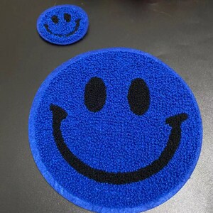 May include: Two blue smiley face patches with black outlines. The larger patch is about 4 inches in diameter and the smaller patch is about 2 inches in diameter.