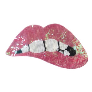Könnte beinhalten: Rosa glitzernde Lippen mit einem weißen und schwarzen Zahn-Design.